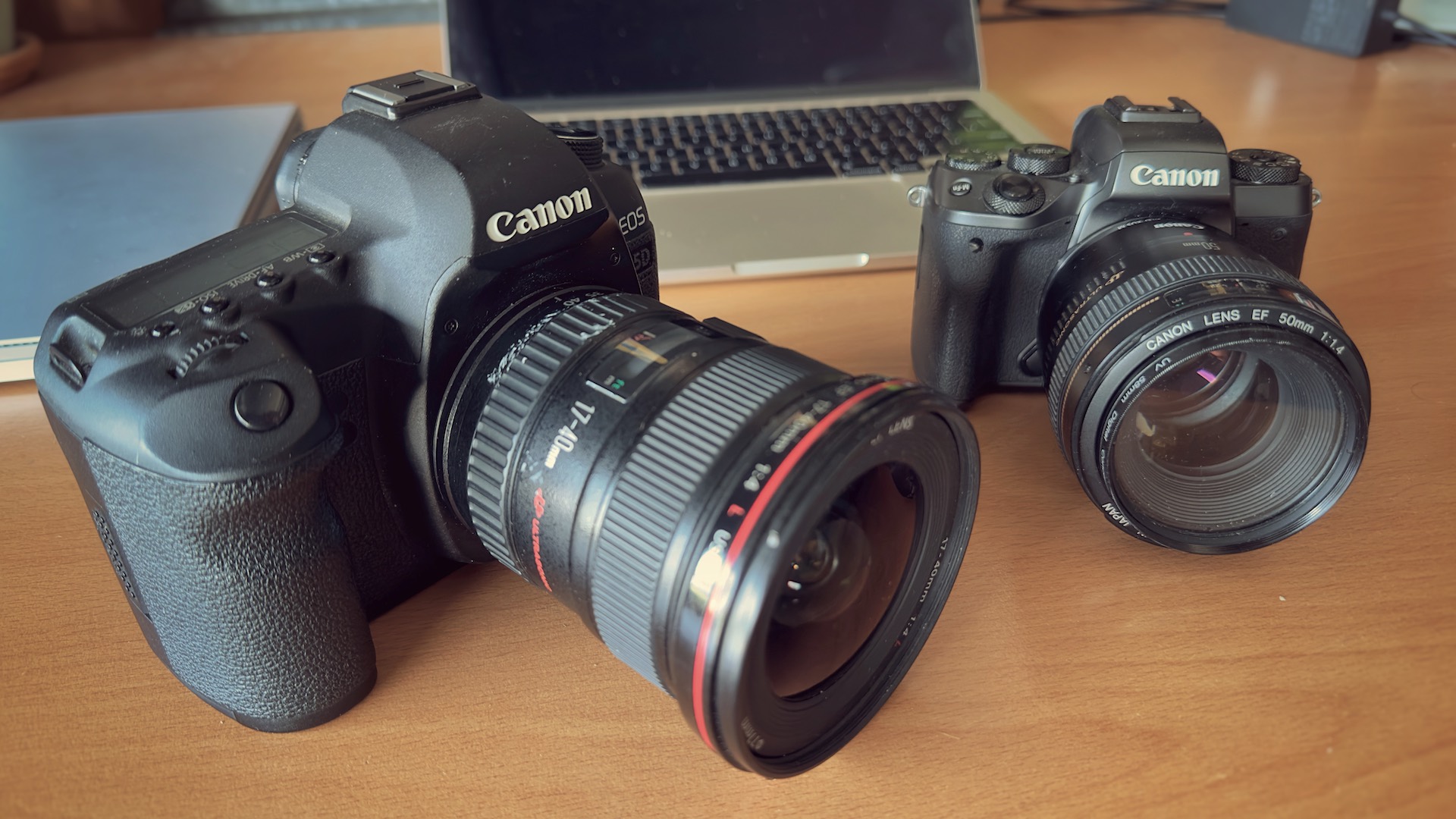 A photo of a canon 5D mark with a 17-40mm lens next ot a canon m5 with a 50mm lens.